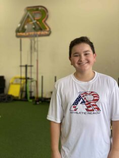 A youth athlete posing for a picture wearing an Athlete Ready 4th of July t-shirt.