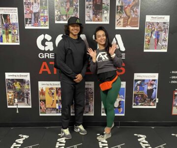 GOATA Roman and Veronica at GOATA lab weekend, posing in front of the GOATA wall.