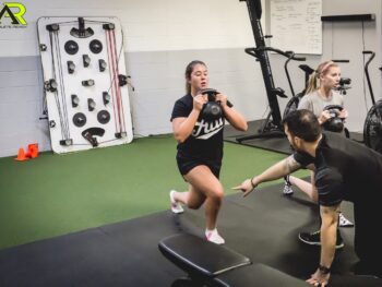 A coach giving instruction to a young woman about plyometrics.