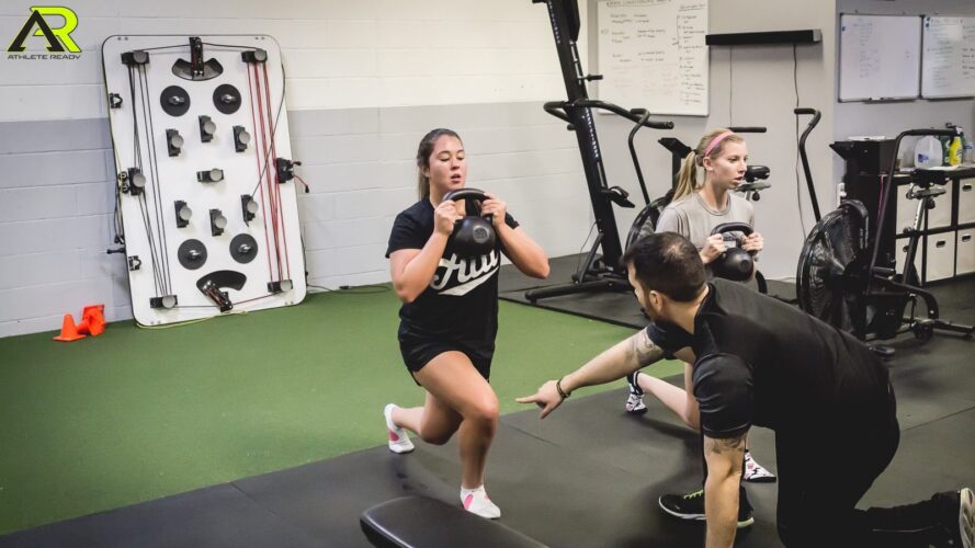 A coach giving instruction to a young woman about plyometrics.