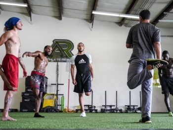 Several MMA athletes warming up and stretching.
