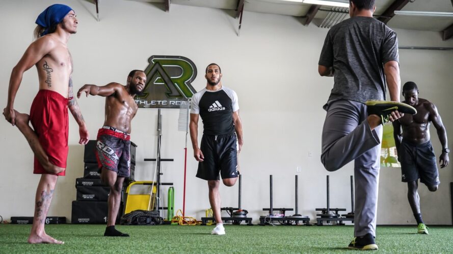 Several MMA athletes warming up and stretching.