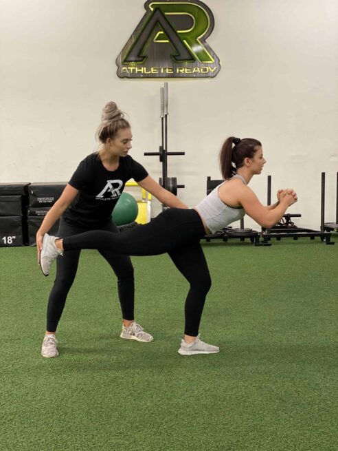 slrdl-coaching A trainer helps a client with their single led Romanian dead lift form.