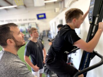 Photo of a coach watching a youth athlete on the Versa Climbing machine.