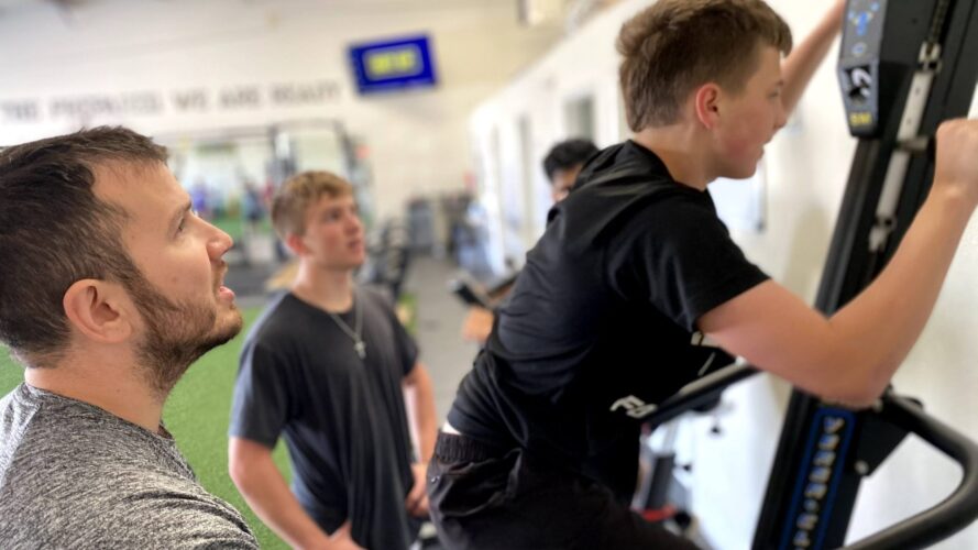 Photo of a coach watching a youth athlete on the Versa Climbing machine.