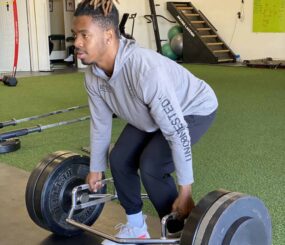 NFL athlete doing a squat with a trap bar.