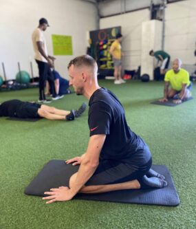 A male athlete sitting in the seiza position and working on gaining access to his back chain.
