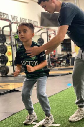 A coach helping a child athlete with his posture.